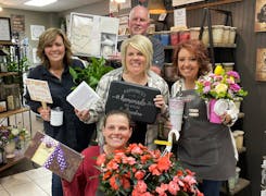 Four members of the FlowerLoft team, with flowers and gifts, inside the flower shop